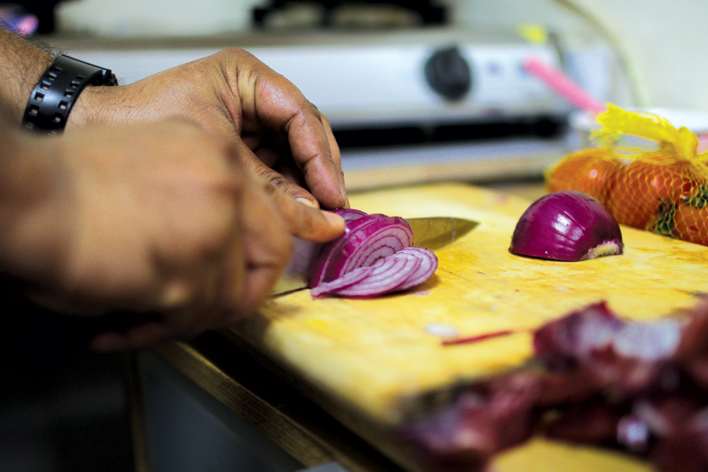 A refugee prepares a meal from his home country (photo by Kevin Cureau)